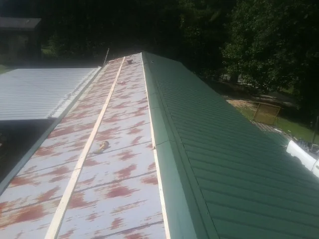 Old rusted panels beside newly installed green metal roofing — Wind Damage Roof Repair by Roofing Brothers in Schnecksville
