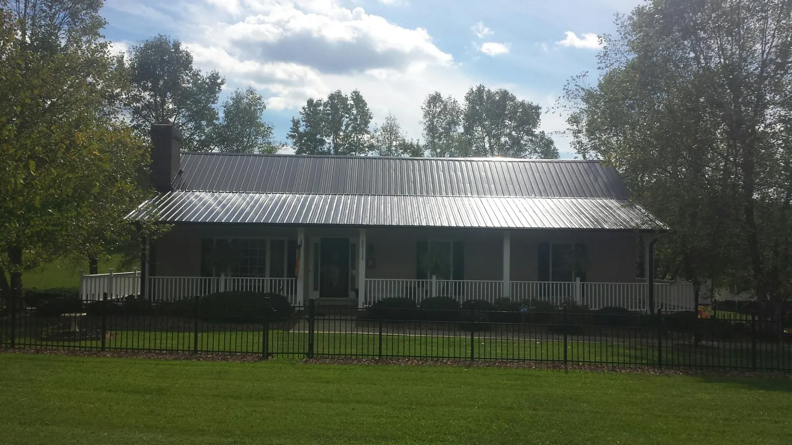 Gray metal roof on a brick ranch with a full width front porch — Gutter Guard Installation work by our crew in Schnecksville