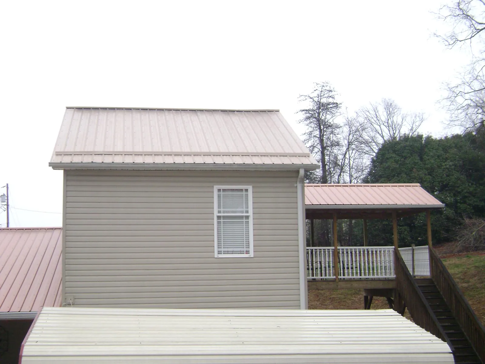 Tan metal roofs on a two story addition and attached porch, from a Roof Replacement job in Schnecksville
