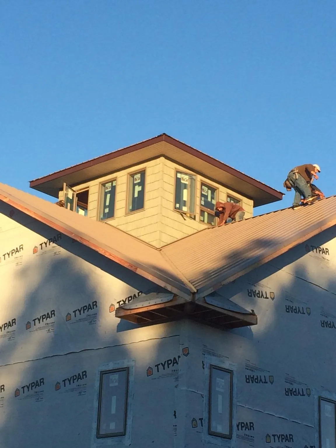 Roofers working around a rooftop cupola on a new metal roof at sunset — Roof Waterproofing in Schnecksville by Roofing Brothers